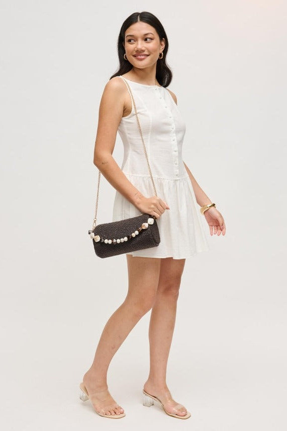 Model carrying the chocolate Rachel Straw Clutch crafted with woven straw texture, faceted beads, polished hardware, and versatile detachable chain.