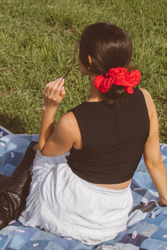 Model wearing the Red Eyelet Jumbo Scrunchie styled in hair, featuring vibrant red stretchy eyelet fabric for a cute and playful look.