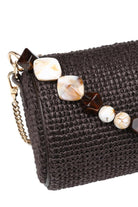 Close-up of the chocolate Rachel Straw Clutch showcasing the textured woven straw exterior, faceted bead embellishments, and polished hardware.