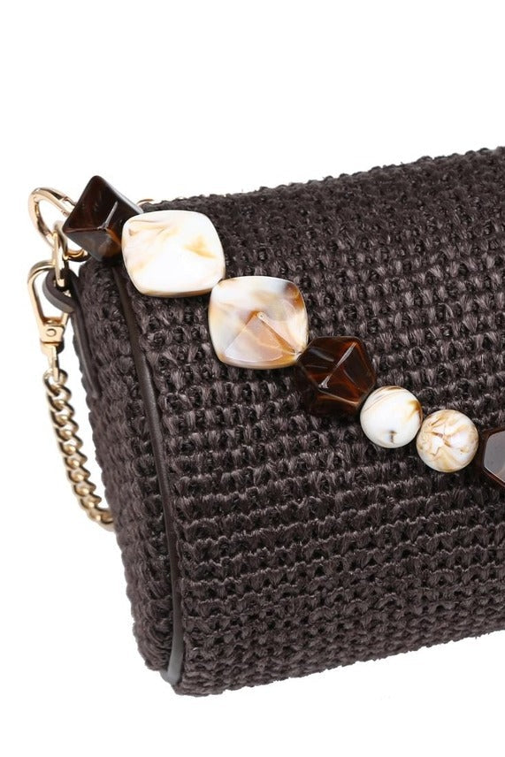 Close-up of the chocolate Rachel Straw Clutch showcasing the textured woven straw exterior, faceted bead embellishments, and polished hardware.
