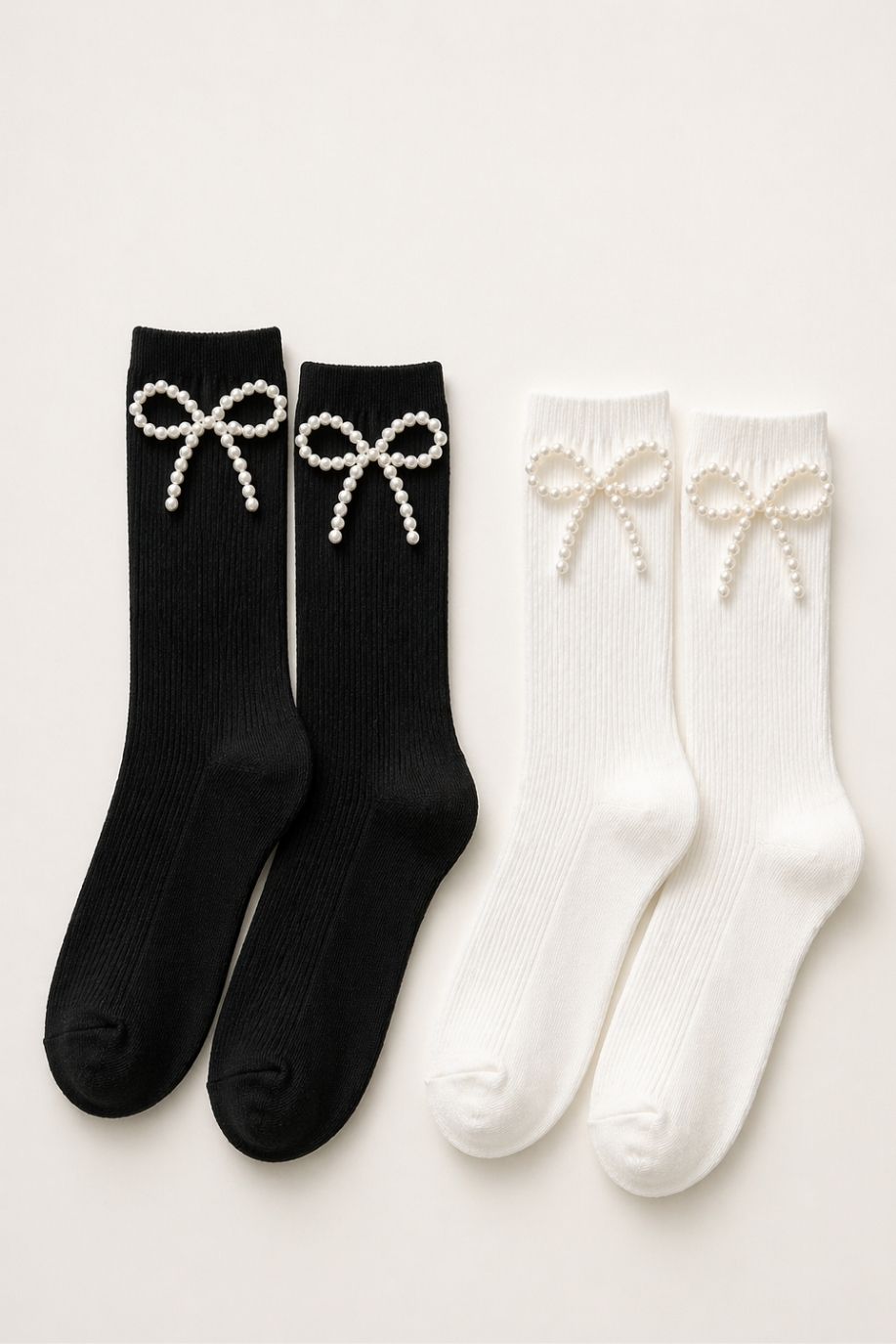 Pearl Bow Classic Ribbed Crew Socks featuring two pairs of ribbed crew socks in black and white, each adorned with a delicate pearl-beaded bow detail at the ankle, displayed on a neutral background.