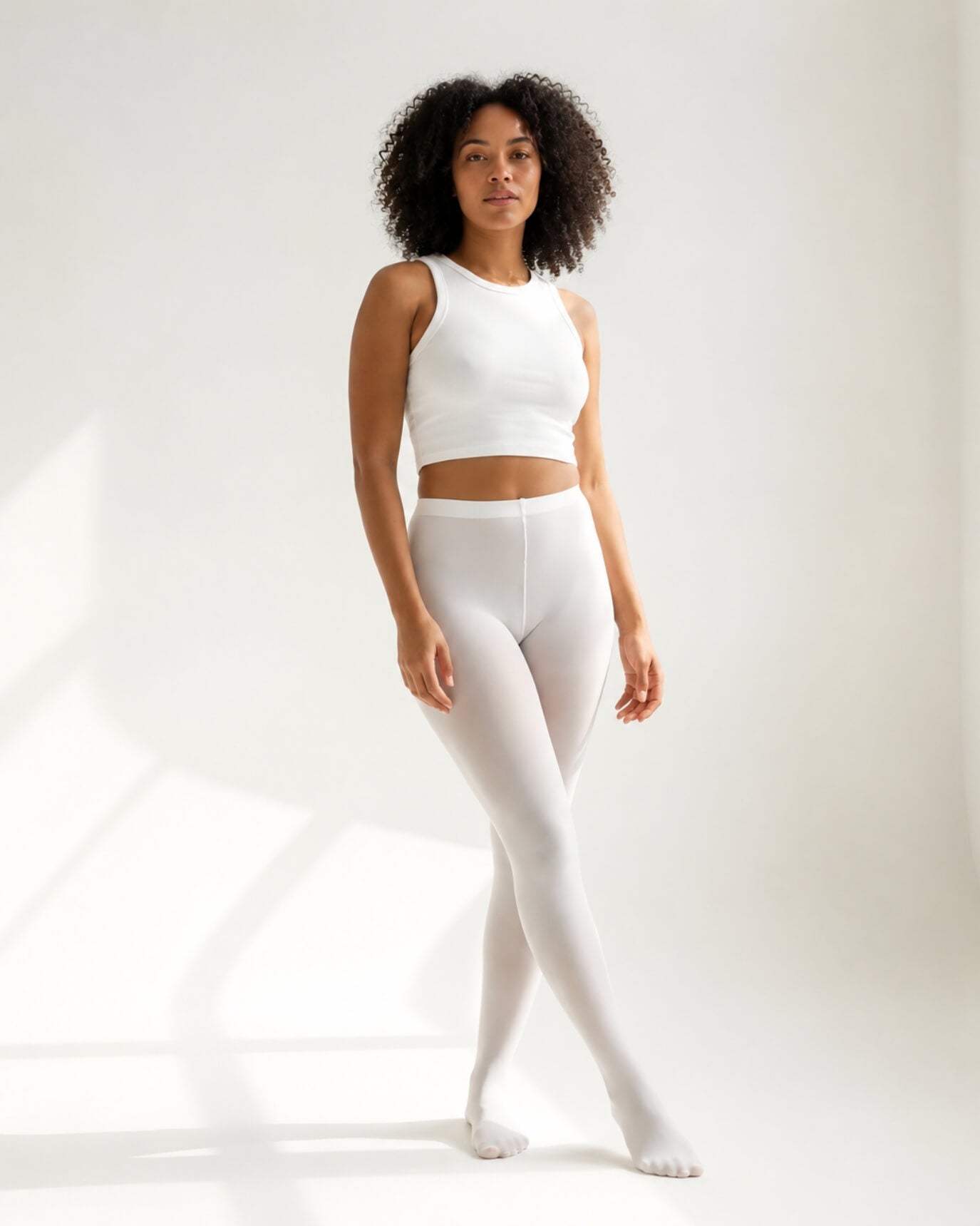 Lightweight Semi Opaque Tights in white, featuring a soft semi-opaque finish with a sleek high-rise waistband, shown full-length on a model in a bright minimalist studio.