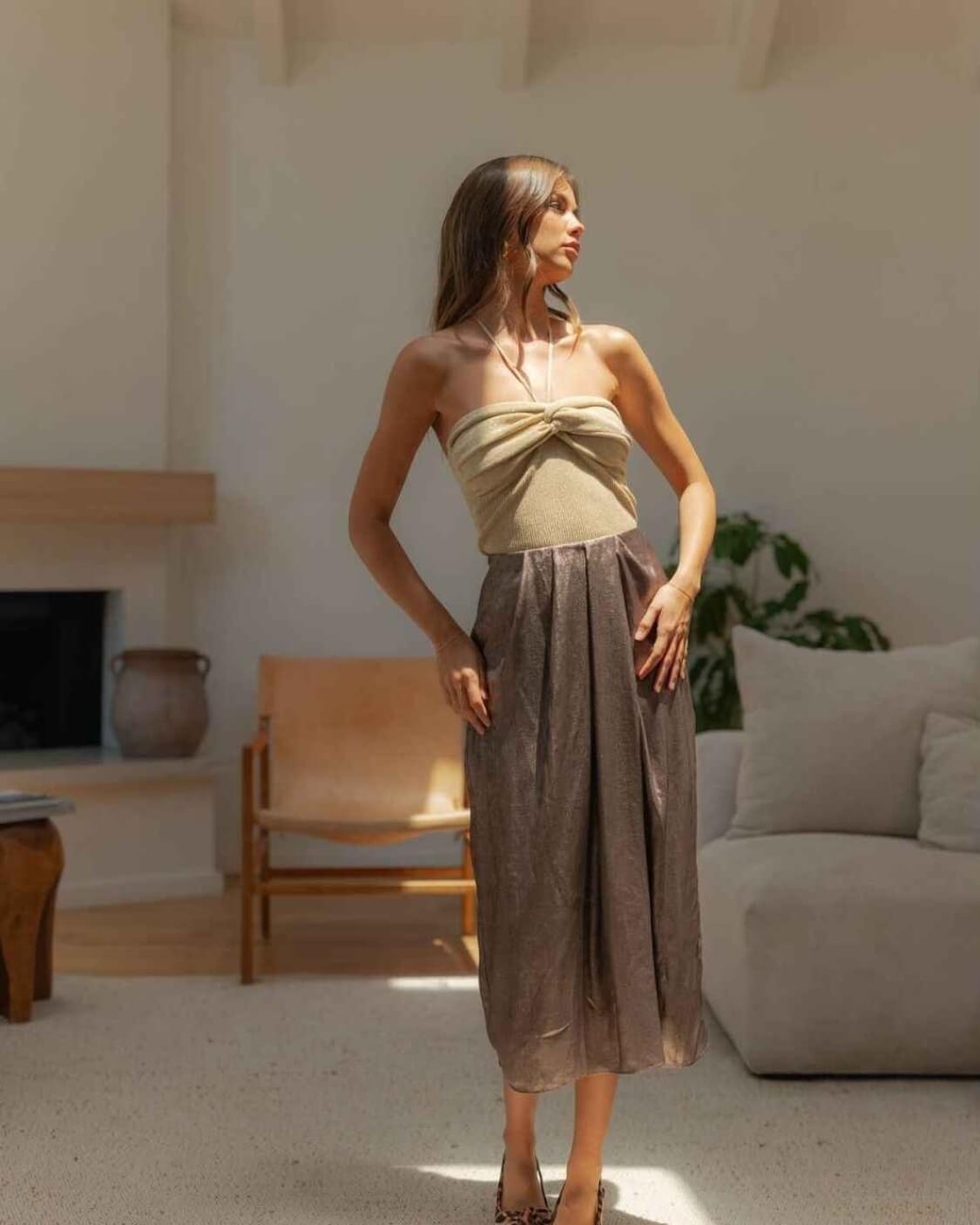 Metallic Fabric Pleat Detailed Skirt featuring a shimmering metallic surface with gathered waist detailing and fluid midi length structure, paired with a fitted halter top and patterned pointed heels, highlighting polished feminine styling and soft texture contrast.