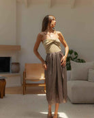 Metallic Fabric Pleat Detailed Skirt featuring a shimmering metallic surface with gathered waist detailing and fluid midi length structure, paired with a fitted halter top and patterned pointed heels, highlighting polished feminine styling and soft texture contrast.
