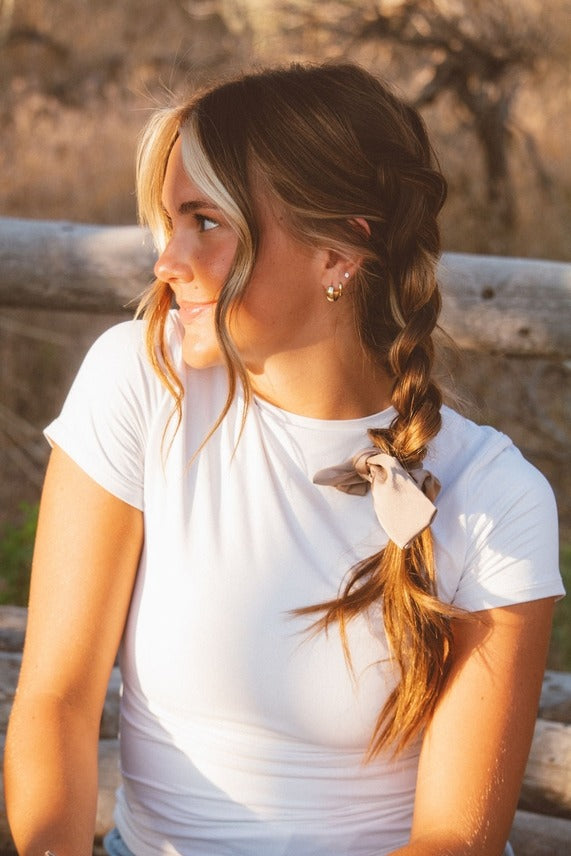 Model styled with the Chestnut Bow Scrunchie in a centipede hairstyle showcasing the elegant bow accent and smooth creamy brown sheen.