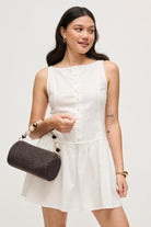 Model wearing the chocolate Rachel Straw Clutch with textured woven exterior, faceted bead detailing, polished hardware, and detachable chain strap.