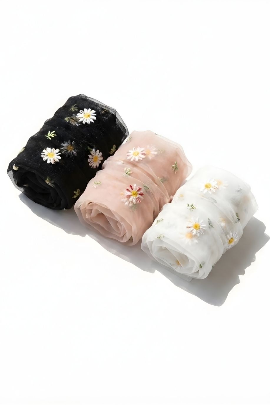 3-pack sheer garden daisy crew socks in black, blush pink, and white, rolled together on a clean white surface to highlight the delicate sheer fabric and embroidered daisy details.