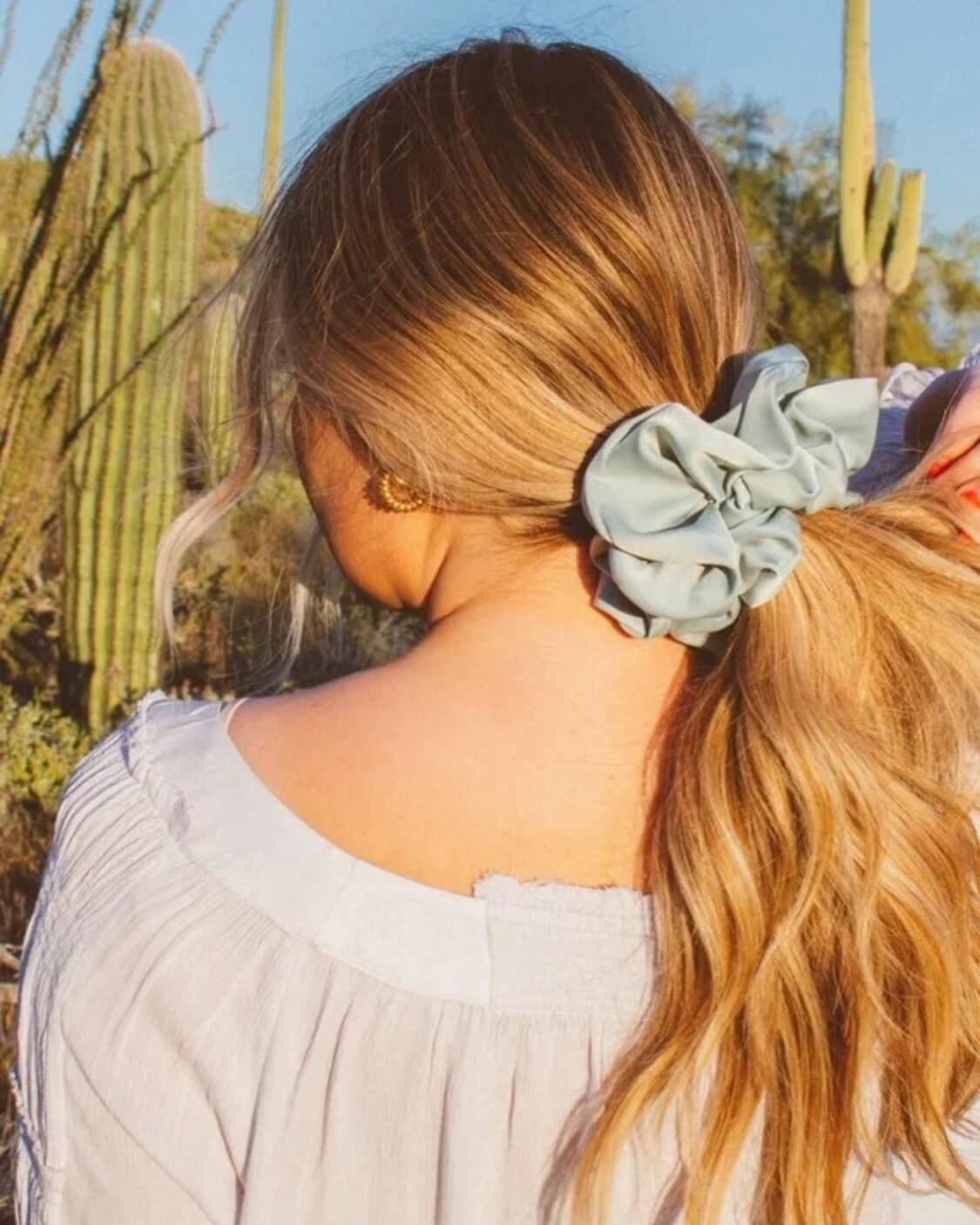 Model shown from the back wearing the Eucalyptus Jumbo Scrunchie featuring matte sateen texture and extra-large design wrapped around a messy bun.