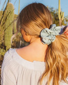 Model shown from the back wearing the Eucalyptus Jumbo Scrunchie featuring matte sateen texture and extra-large design wrapped around a messy bun.