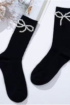 Black ribbed crew socks featuring delicate pearl bow embellishments, styled flat lay on a light background.