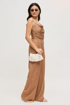 Model holding a compact opalite evening bag that reflects light with an iridescent shine.