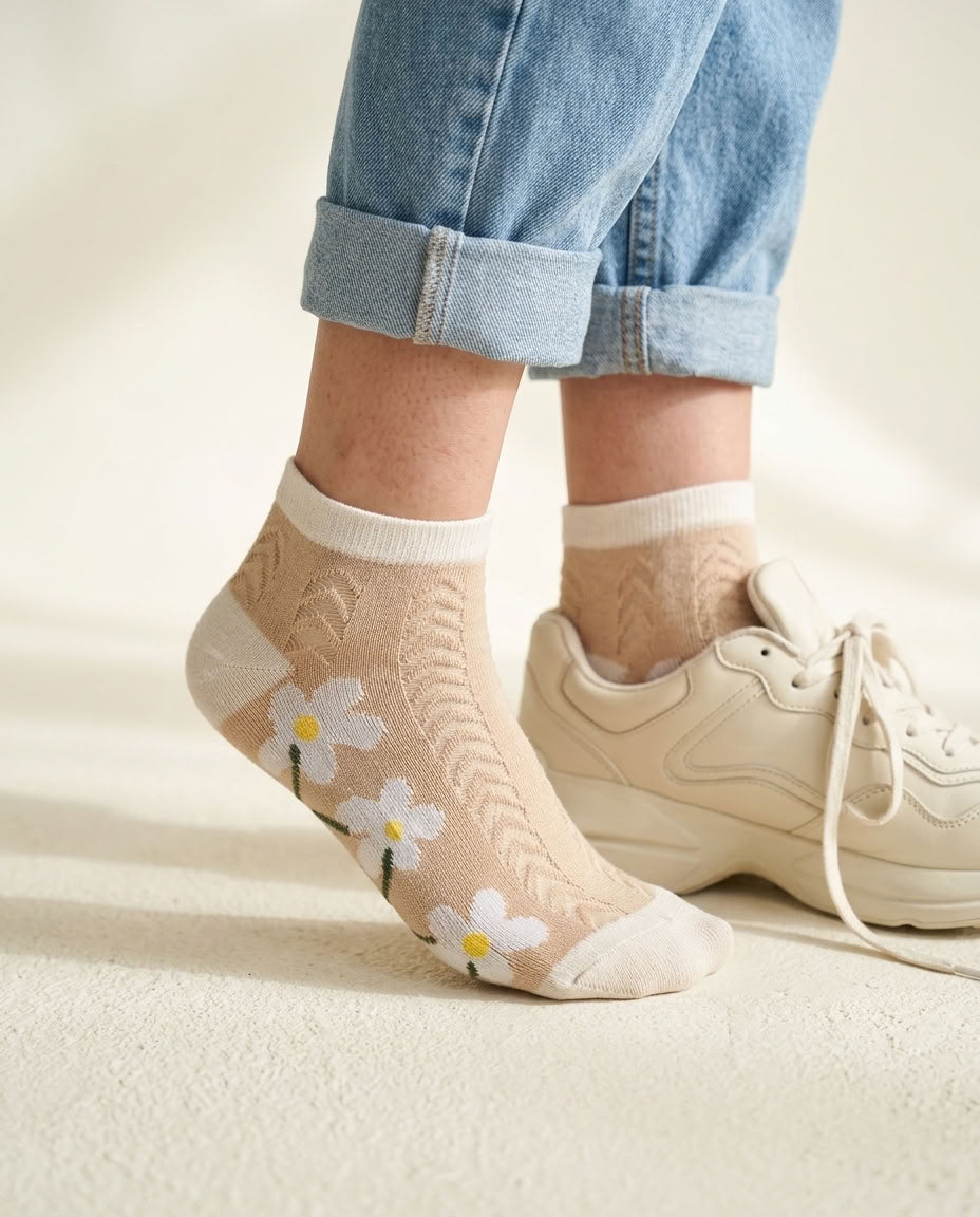Beige daisy pointelle low-cut socks with cream trim beside a cream sneaker