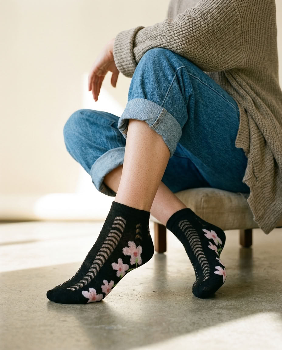 Black daisy pointelle low-cut socks with pink flowers worn with cuffed jeans