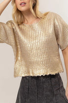 Model wearing the gold Metal Coated Knit Sweater with round neckline, relaxed short sleeves, chunky knit texture, and lettuce-edged hem.