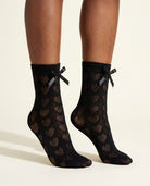 Black Heart-Shaped Lace Bow Socks, close-up on tiptoe showing open-knit hearts and satin bows